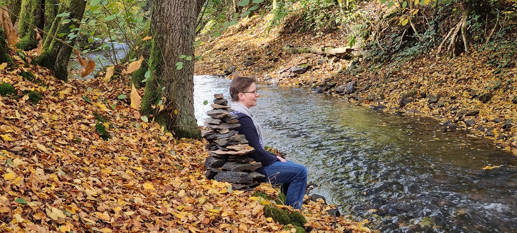 Der Eifgenbach in herbstlicher Stimmung. Naturpur Gudula Burghoff am Bach sitzend